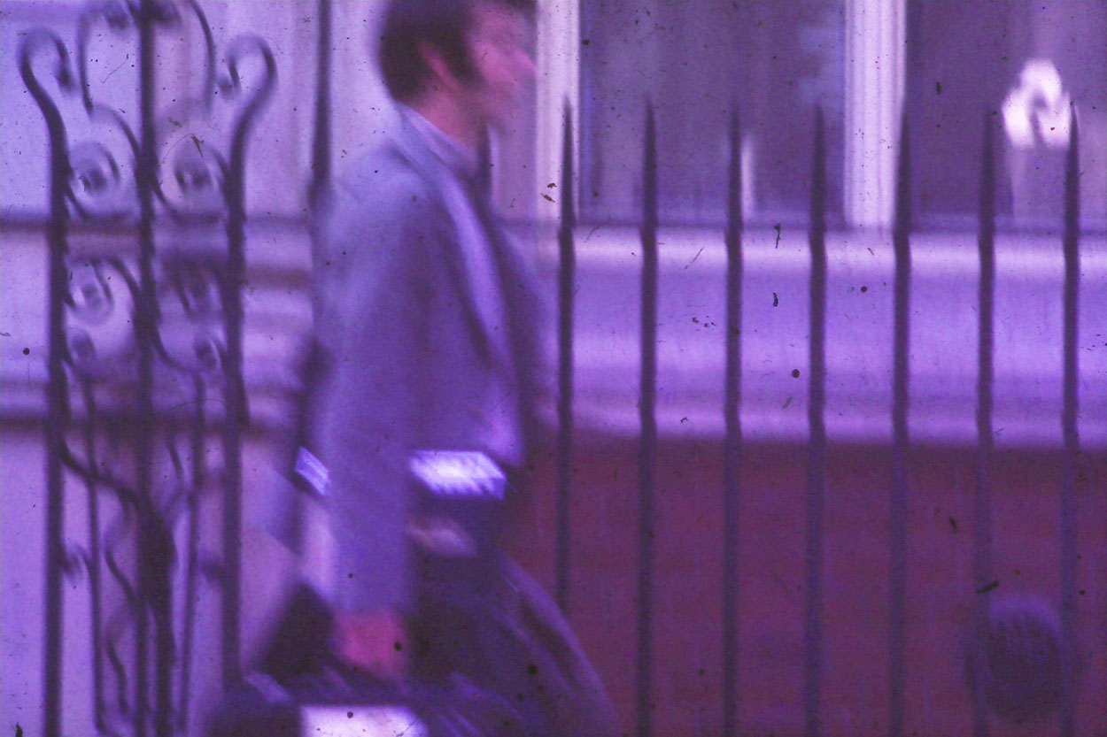 Man by some railings. On the street in london in old photo.