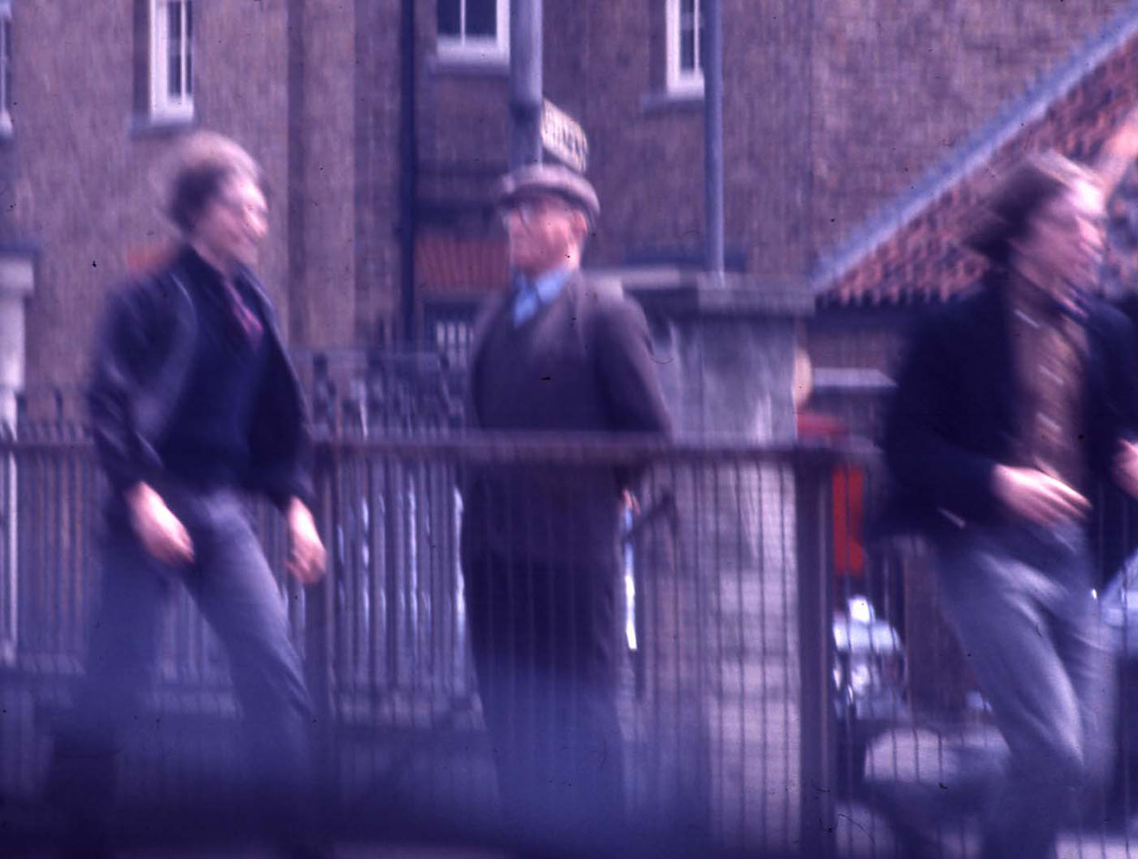 It's grim down south. 2 men walk past an aged onlooker.